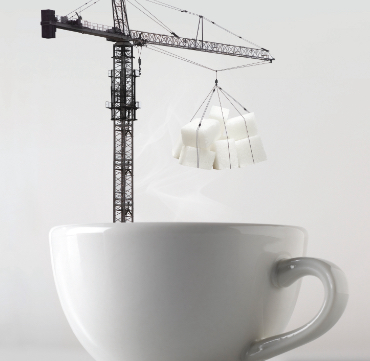 crane lowering sugar cubes into a cup of hot coffee
