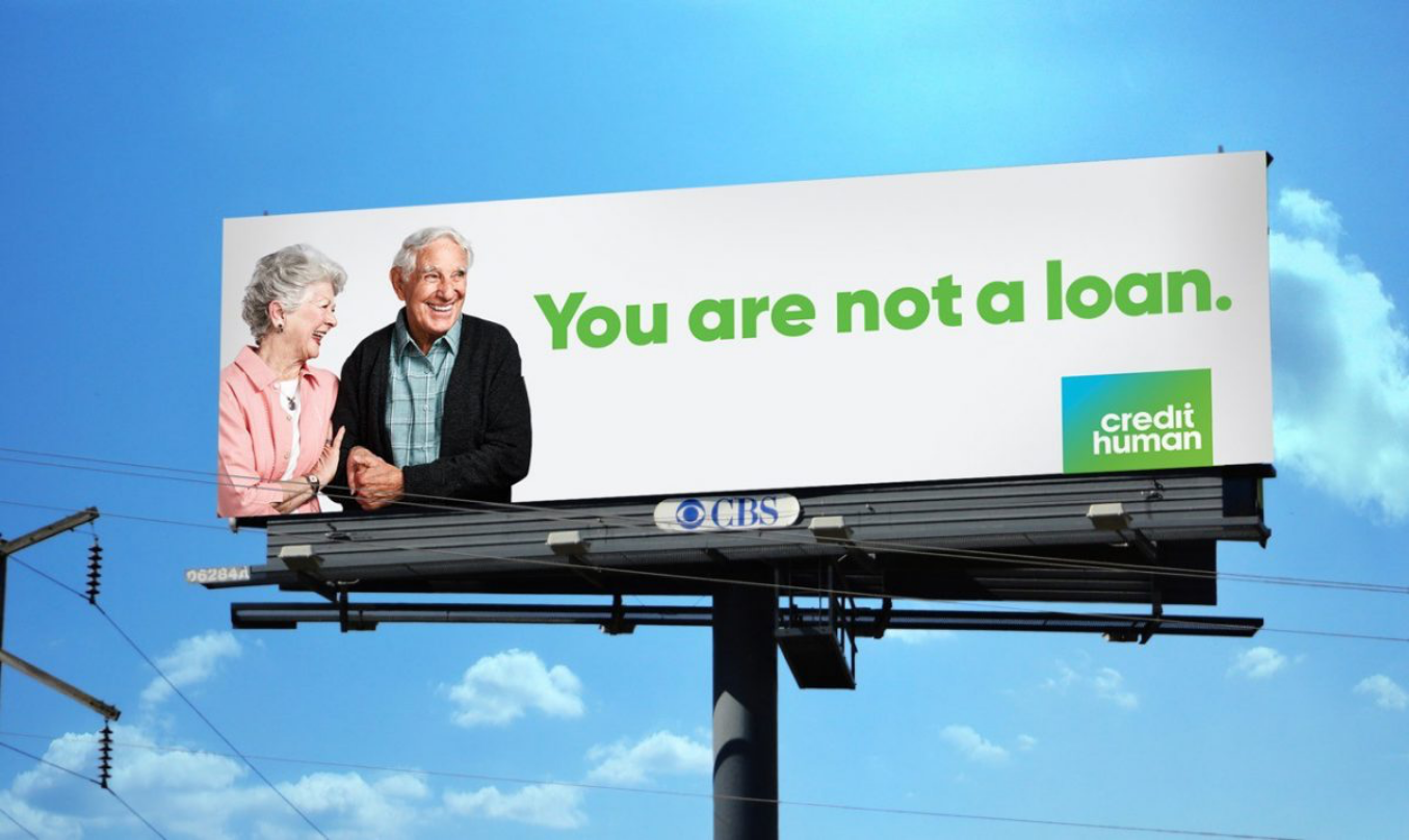 elterly couple holding hands and locking arms while smiling on a billboard supporting loans from credit human